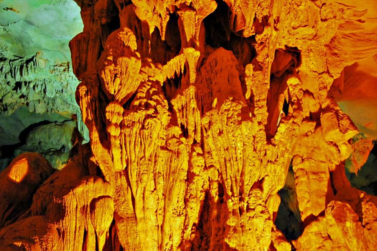 Close-up of orange-hued stalactites and rock formations inside Dau Go Cave Halong Bay, richly textured and detailed.