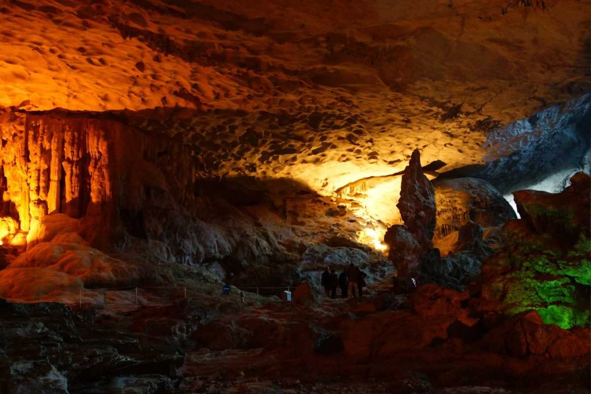 Spacious interior of Dau Go Cave Halong Bay showing rocky floor and illuminated ceiling formations.
