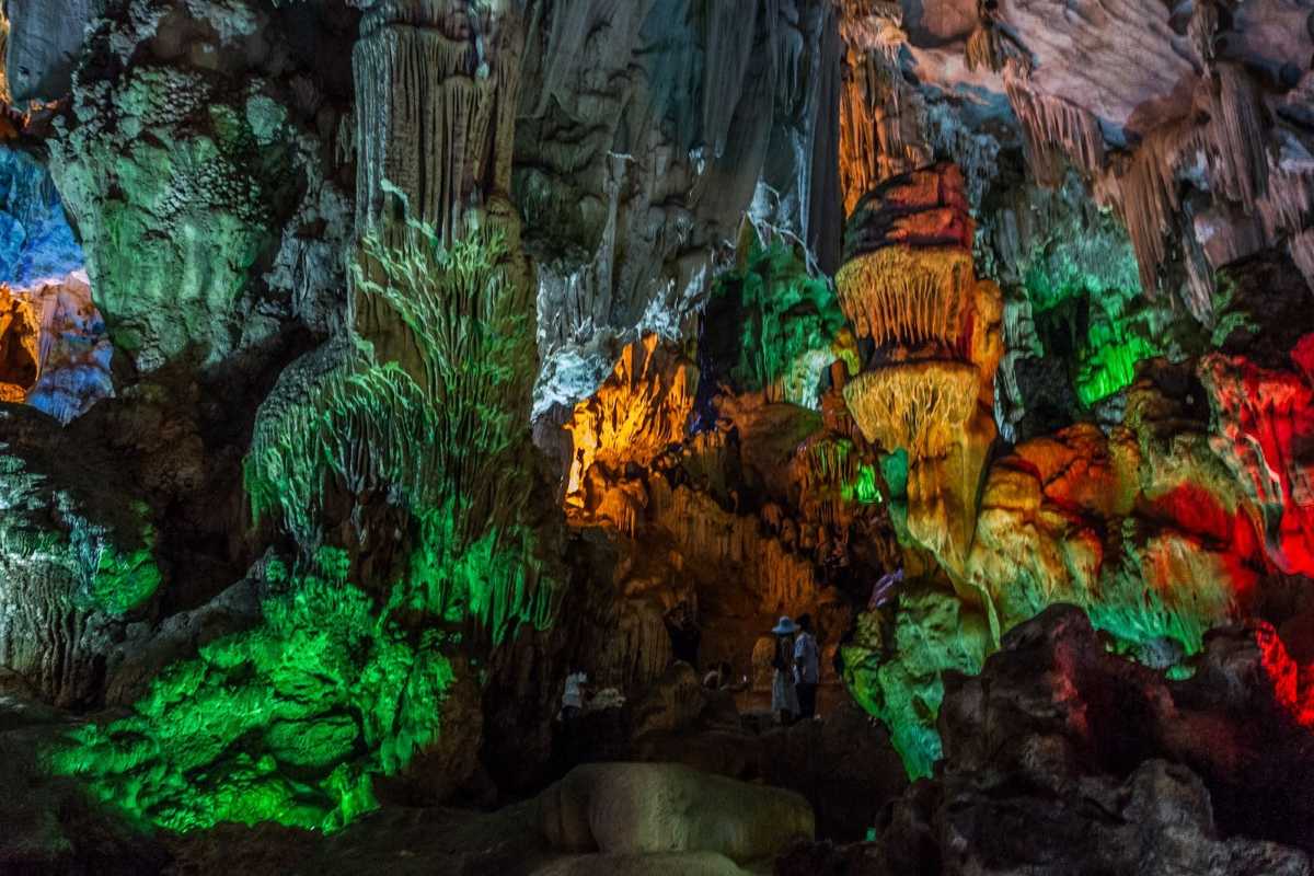 Vibrant and colorful interior lighting showcasing natural rock formations inside Dau Go Cave Halong Bay.