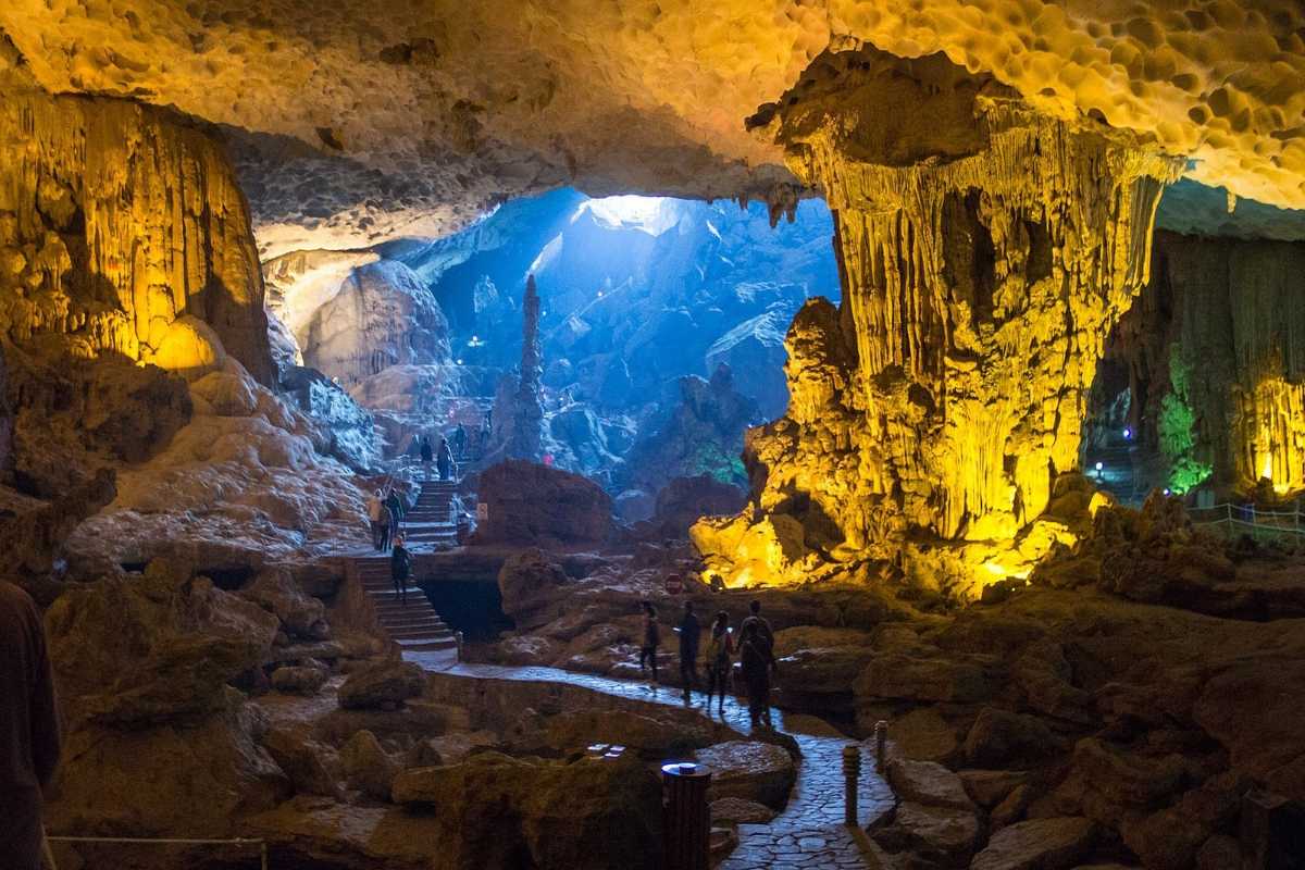 Wide view of Dau Go Cave Halong Bay’s interior showing visitors walking along pathways under colorful lighting.