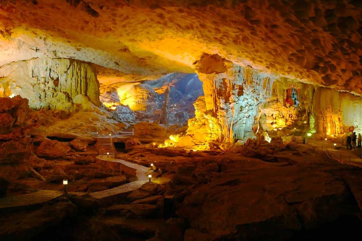 Wide interior shot of Dau Go Cave Halong Bay showing visitors exploring the illuminated rocky formations.