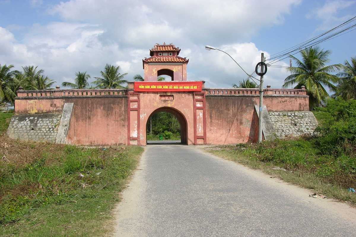 Straight-on view of Dien Khanh Citadel gate with a red national banner and blue skies.