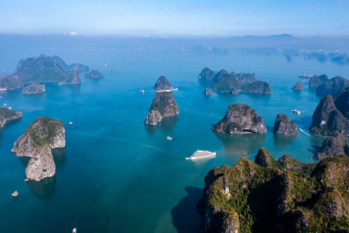 Aerial view of Dinh Huong Islet Halong Bay showcasing limestone karsts surrounded by emerald waters and cruise boats