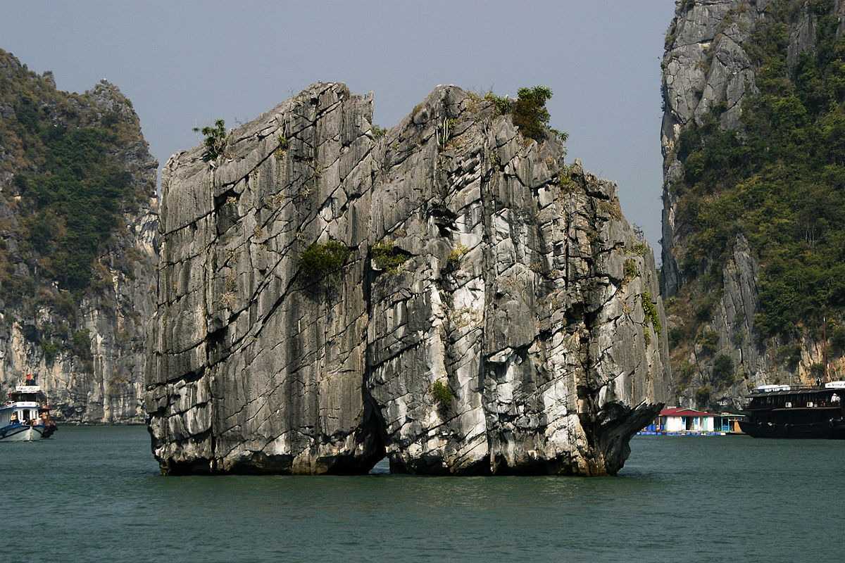 Close-up of the iconic limestone rock formation at Dinh Huong Islet Halong Bay surrounded by boats and cliffs