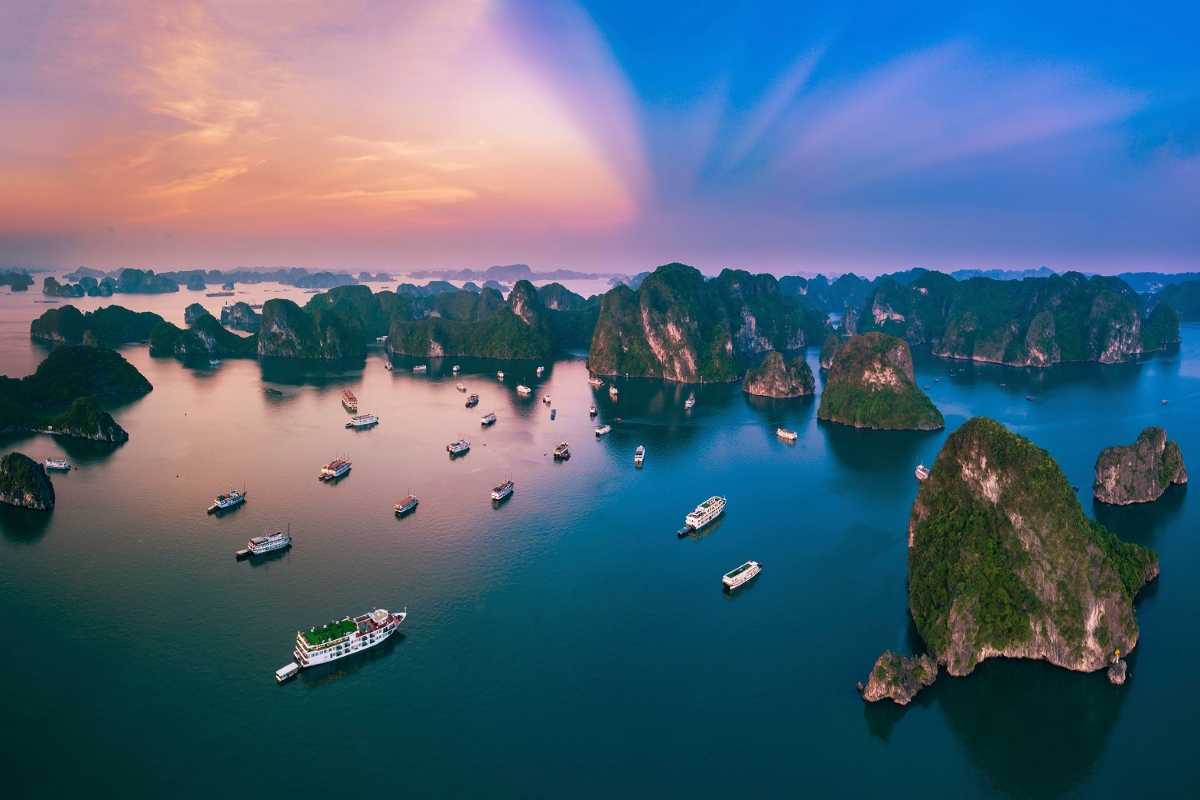 Limestone formation glowing in the sunset light at Dinh Huong Islet Halong Bay with boats nearby