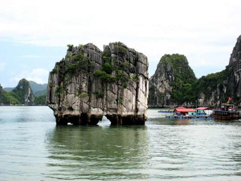 Dinh Huong Islet in Halong Bay with Boats Nearby Dinh Huong Islet in Halong Bay with boats nearby, highlighting its popular tourist spot amidst the natural beauty of the bay.