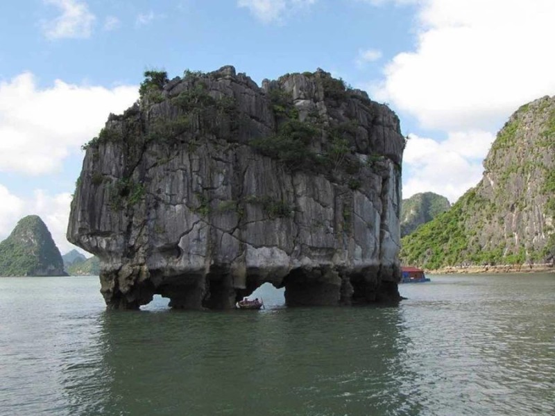 Dinh Huong Islet with Surrounding Limestone Formations Dinh Huong Islet in Halong Bay surrounded by limestone formations, captured from a boat view.