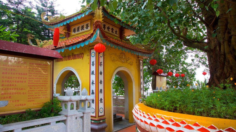 Entrance gate of Tran Quoc Pagoda in Hanoi, featuring traditional yellow walls, red lanterns, and intricate Buddhist inscriptions.