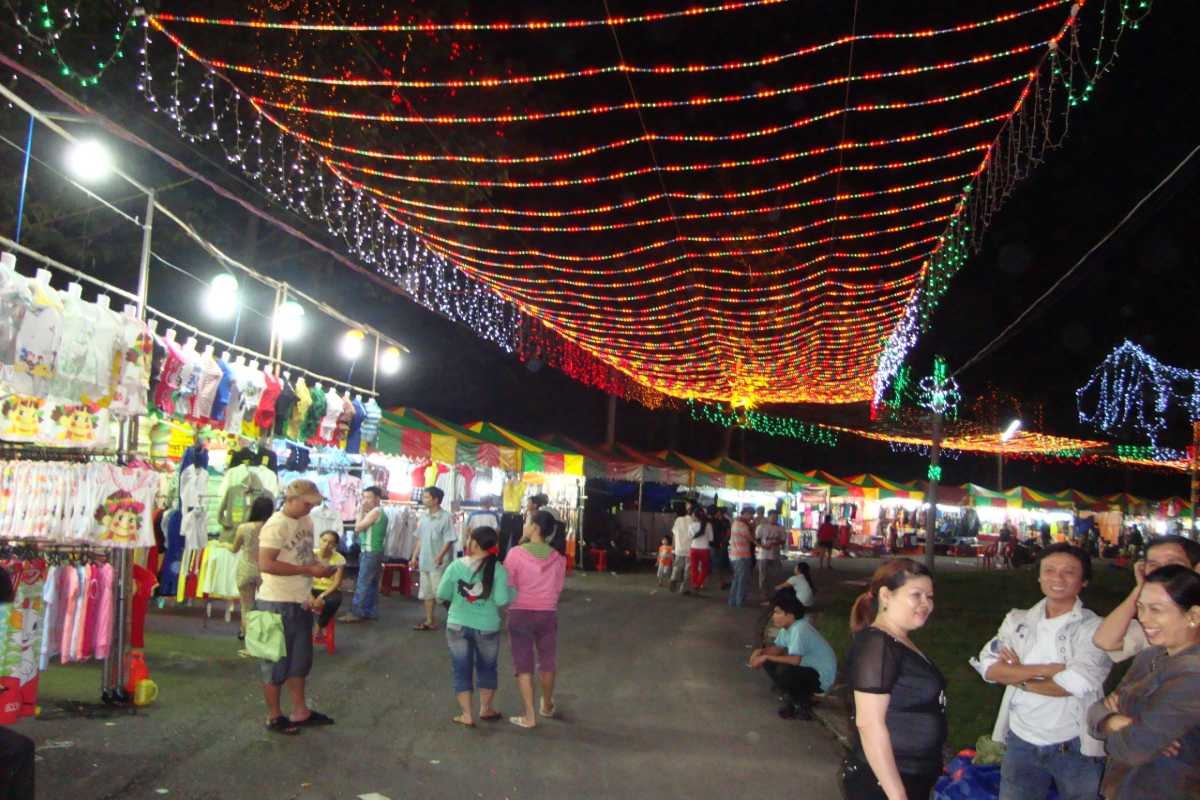 Evening Crowd at Nha Trang Night Market Locals and tourists browsing stalls filled with clothing and lights in Nha Trang Night Market