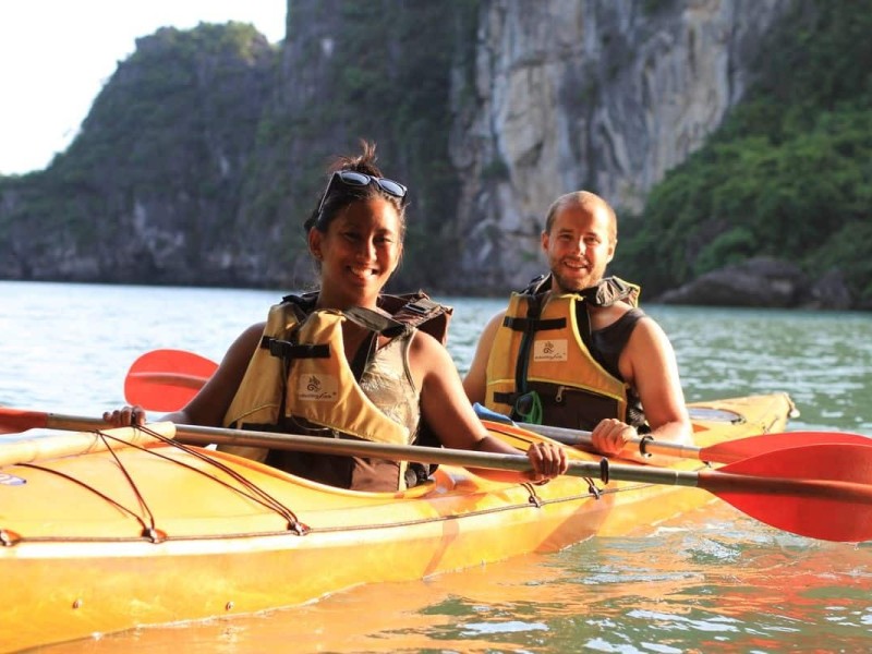 Kayaking across scenic waters of Ha Long Bay with limestone karsts in the background.