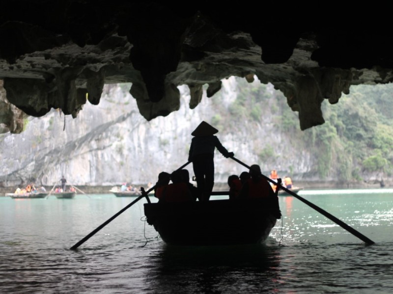 Exploring the Serene Waters of Dark and Light Caves by Boat Visitors exploring the peaceful waters of Dark and Light Caves by boat in Ha Long Bay.