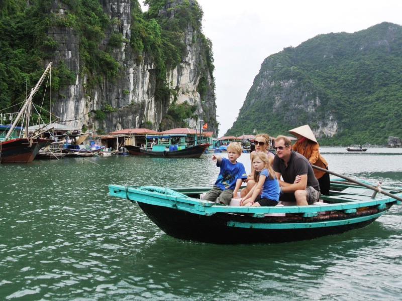 Family Enjoying a Boat Tour at Cua Van Floating Village A family enjoying a boat tour in Cua Van Floating Village in Halong Bay, with limestone cliffs in the background.