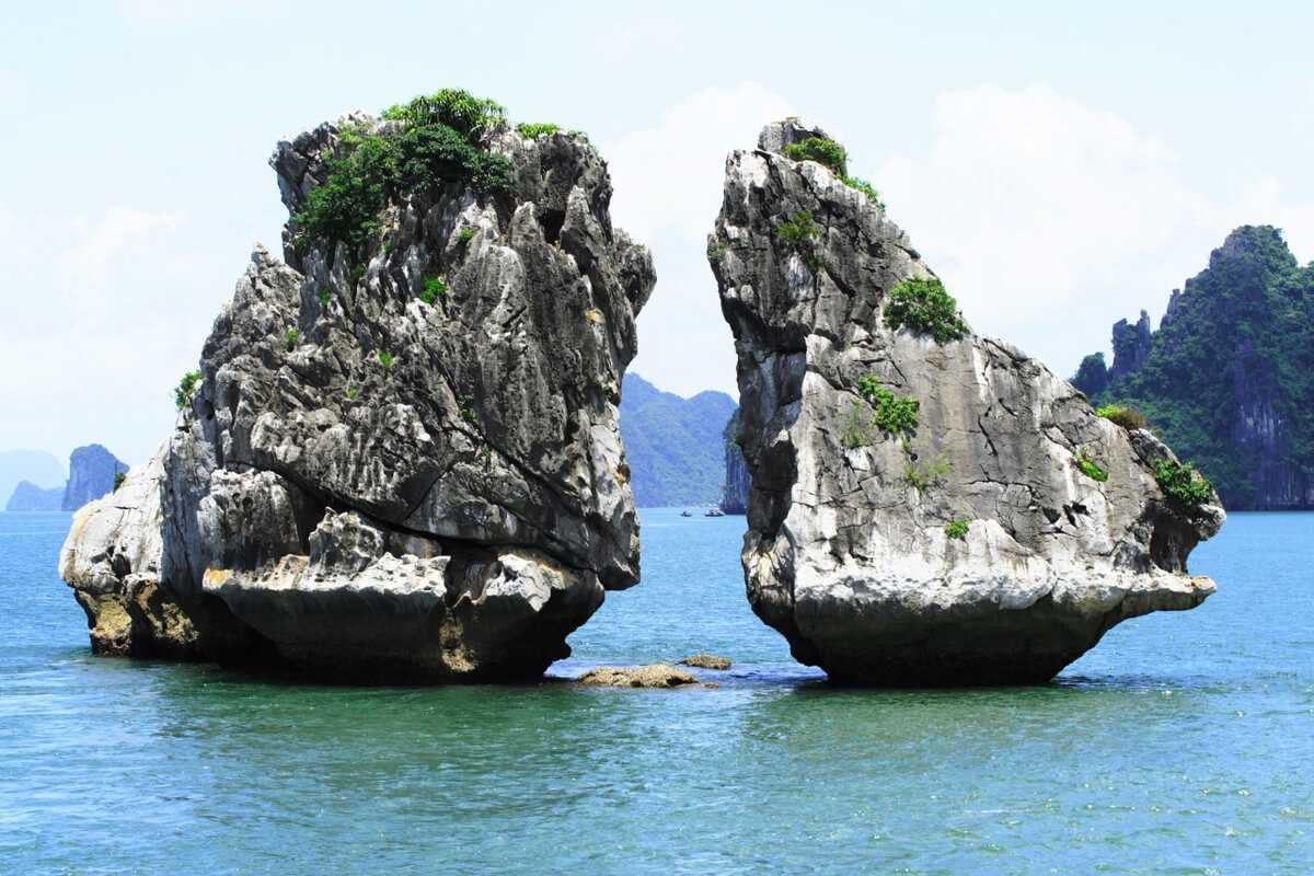 Iconic twin limestone rocks of Fighting Cocks Islet Halong Bay standing in emerald water
