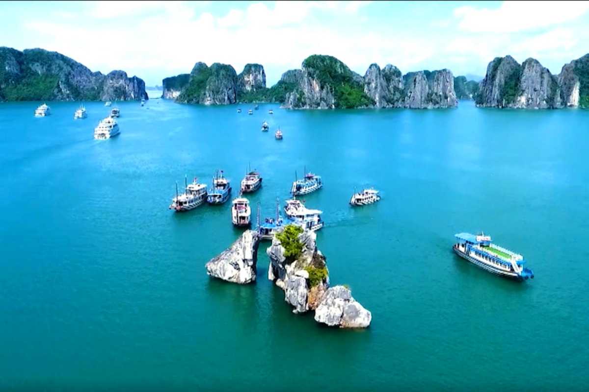 Sightseeing boat with tourists near Fighting Cocks Islet Halong Bay limestone formations