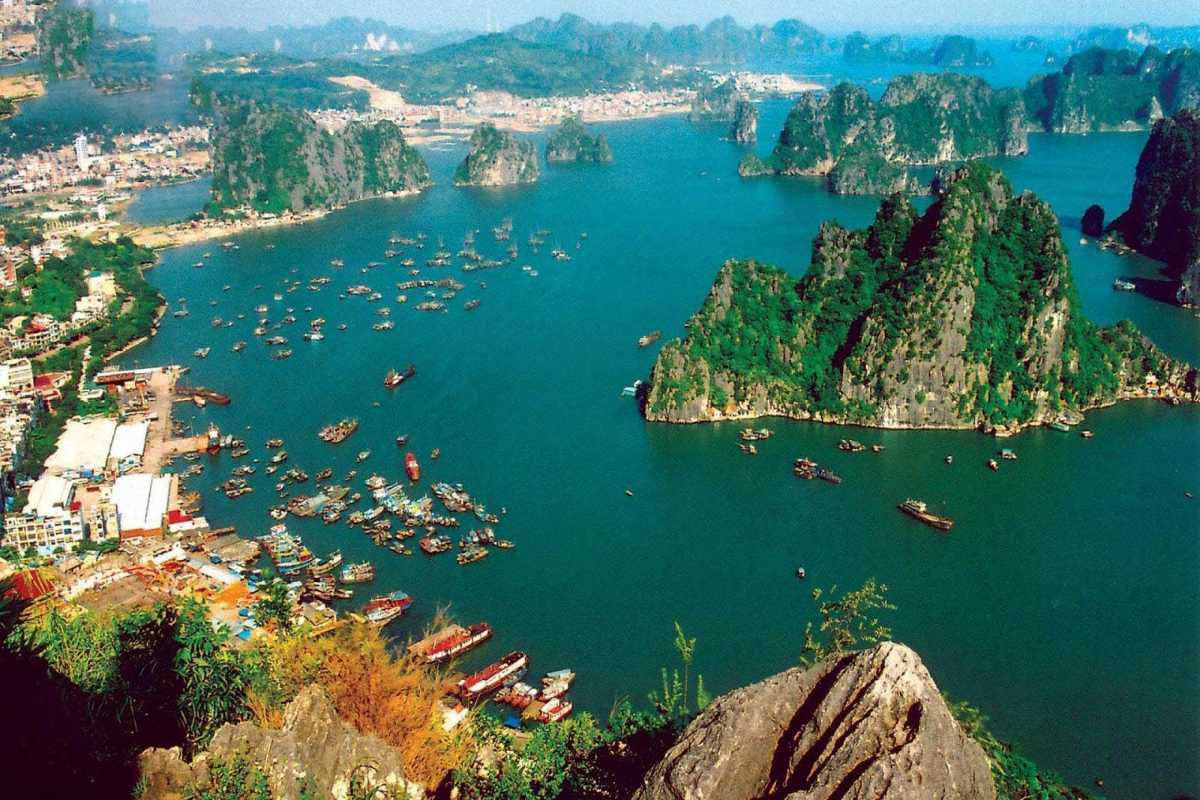 Boats and floating houses on emerald waters surrounded by karst cliffs in Cong Dam Bay