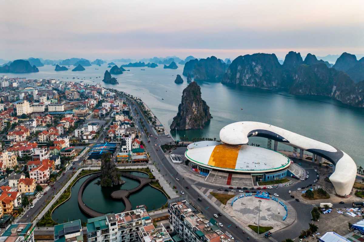 Aerial view of Ha Long City with limestone islands scattered in the bay under soft sunset light.