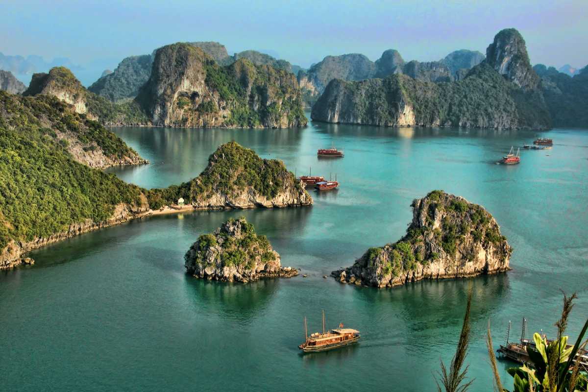 Scenic panoramic view of Ha Long Bay with numerous limestone islands and boats floating on emerald waters.