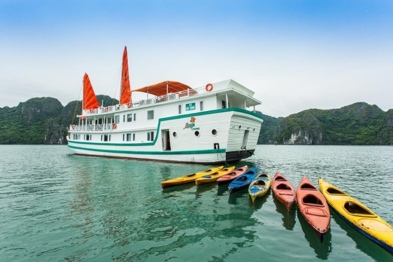 halong-bay-cruise-kayaking-titov-island.jpg A white cruise boat docked in Halong Bay with colorful kayaks in the foreground, ready for an adventure near Titov Island.