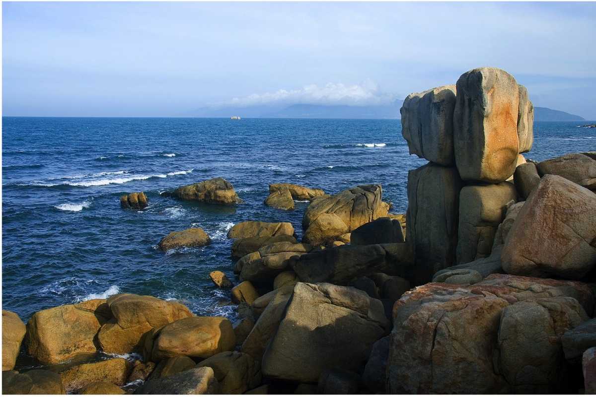 Rock formations at Hon Chong Promontory with Nha Trang city buildings visible