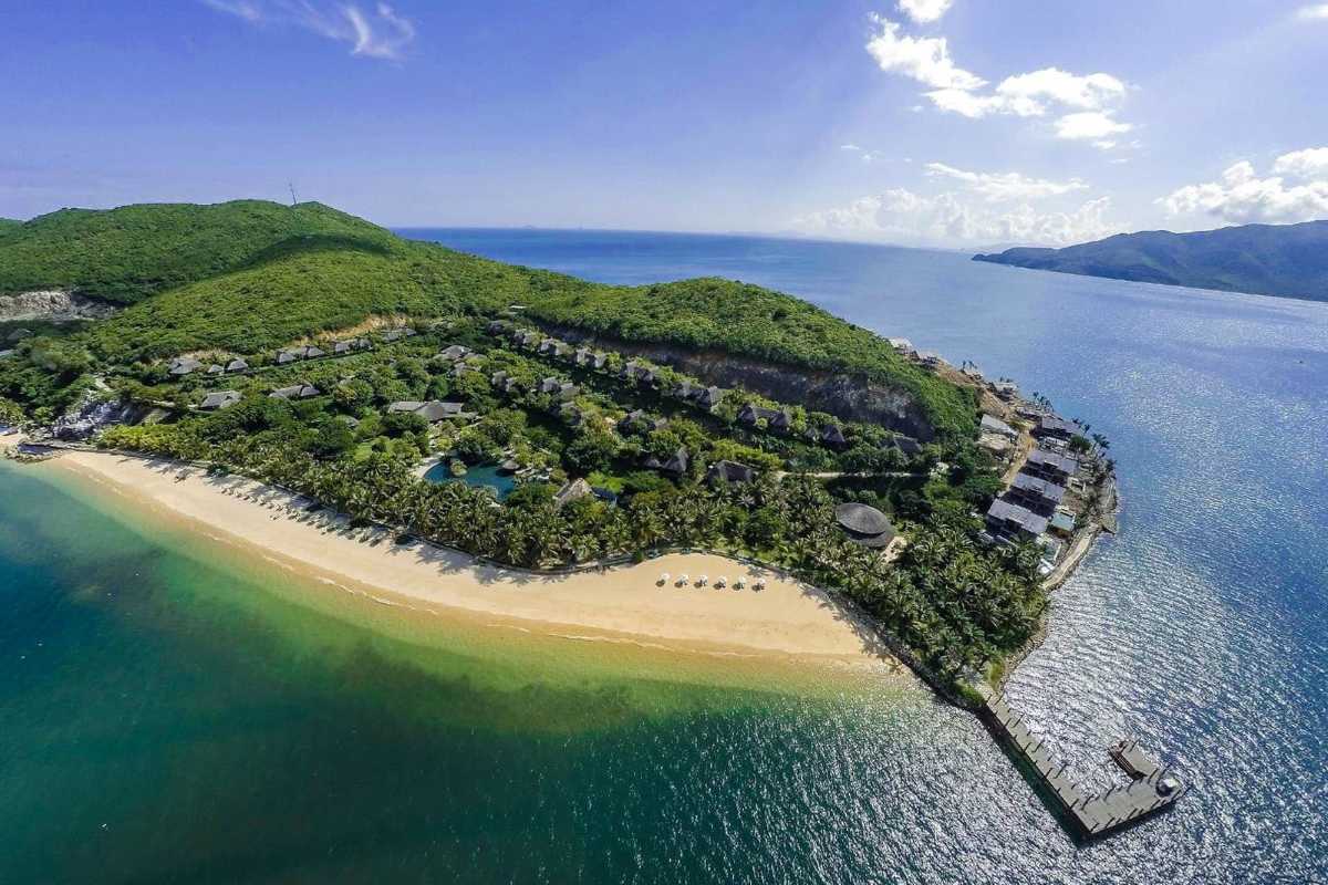 Tranquil view of Hon Mun’s private bay, golden beach and vibrant sea surrounded by palm-dotted hills.
