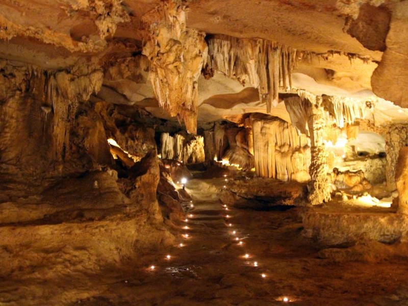 The illuminated interior of Thien Canh Son Cave showing intricate rock formations.