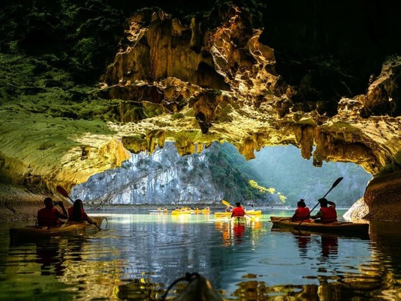 Kayakers Entering the Hidden Beauty of Dark and Light Caves Kayakers entering the stunning Dark and Light Caves, revealing hidden natural beauty in Ha Long Bay.