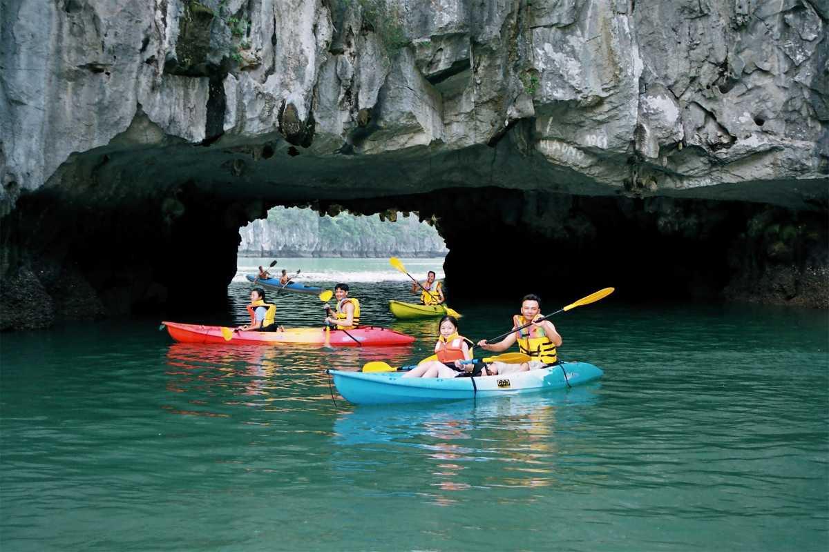 Smiling local boatmen guiding kayakers near Luon Cave surrounded by limestone cliffs