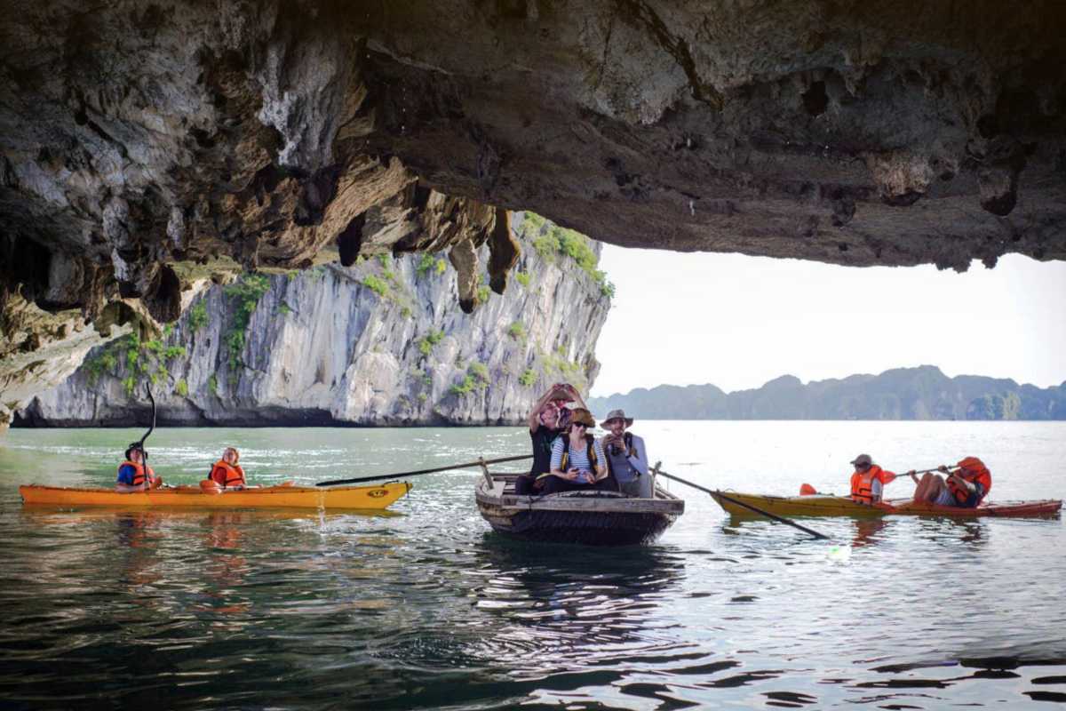 Kayakers maneuvering beneath the rocky ceiling of Luon Cave inside Halong Bay
