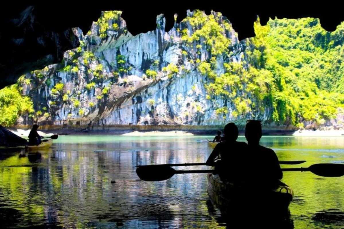Scenic limestone cliffs towering over kayakers in vibrant kayaks at Luon Cave Halong Bay