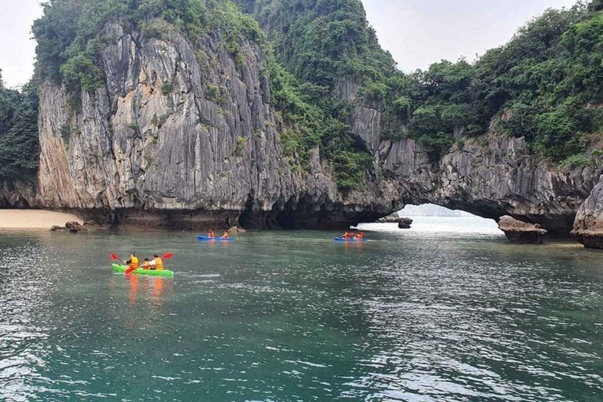 Kayaking Luon Cave Halong Bay showcasing colorful kayaks navigating through a scenic water passage beneath limestone cliffs