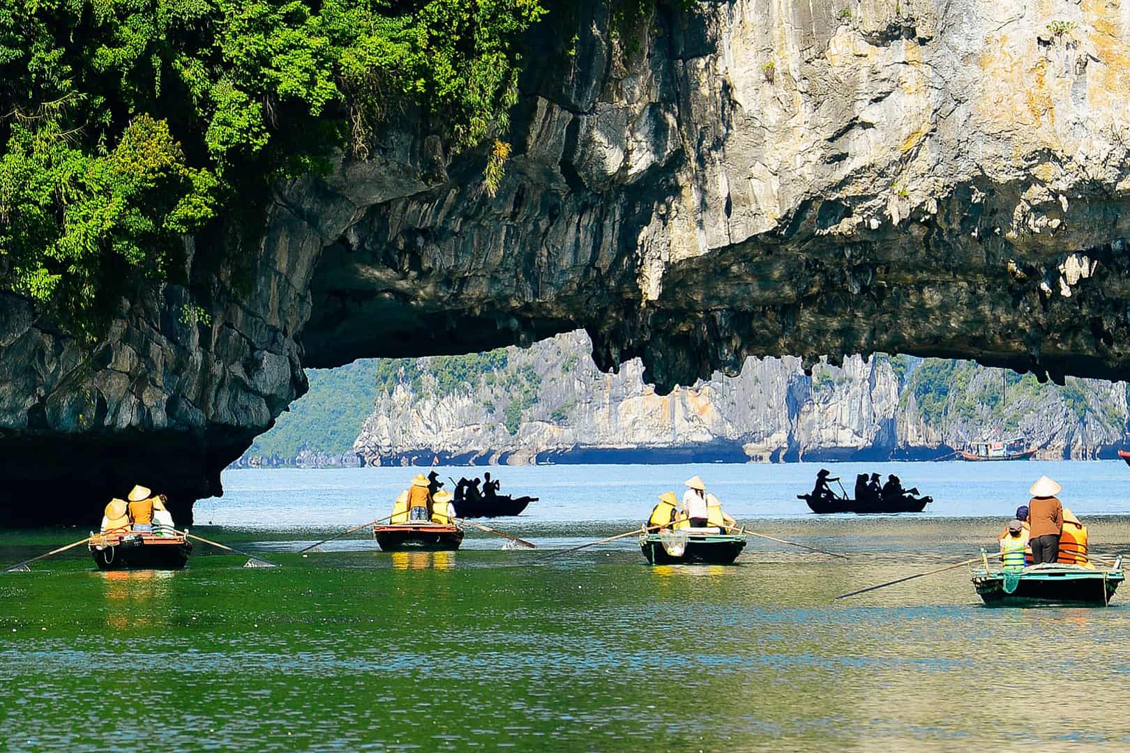 Kayaking Through the Stunning Luon Cave Kayakers exploring Luon Cave's tranquil lagoon, surrounded by towering limestone cliffs in Ha Long Bay.