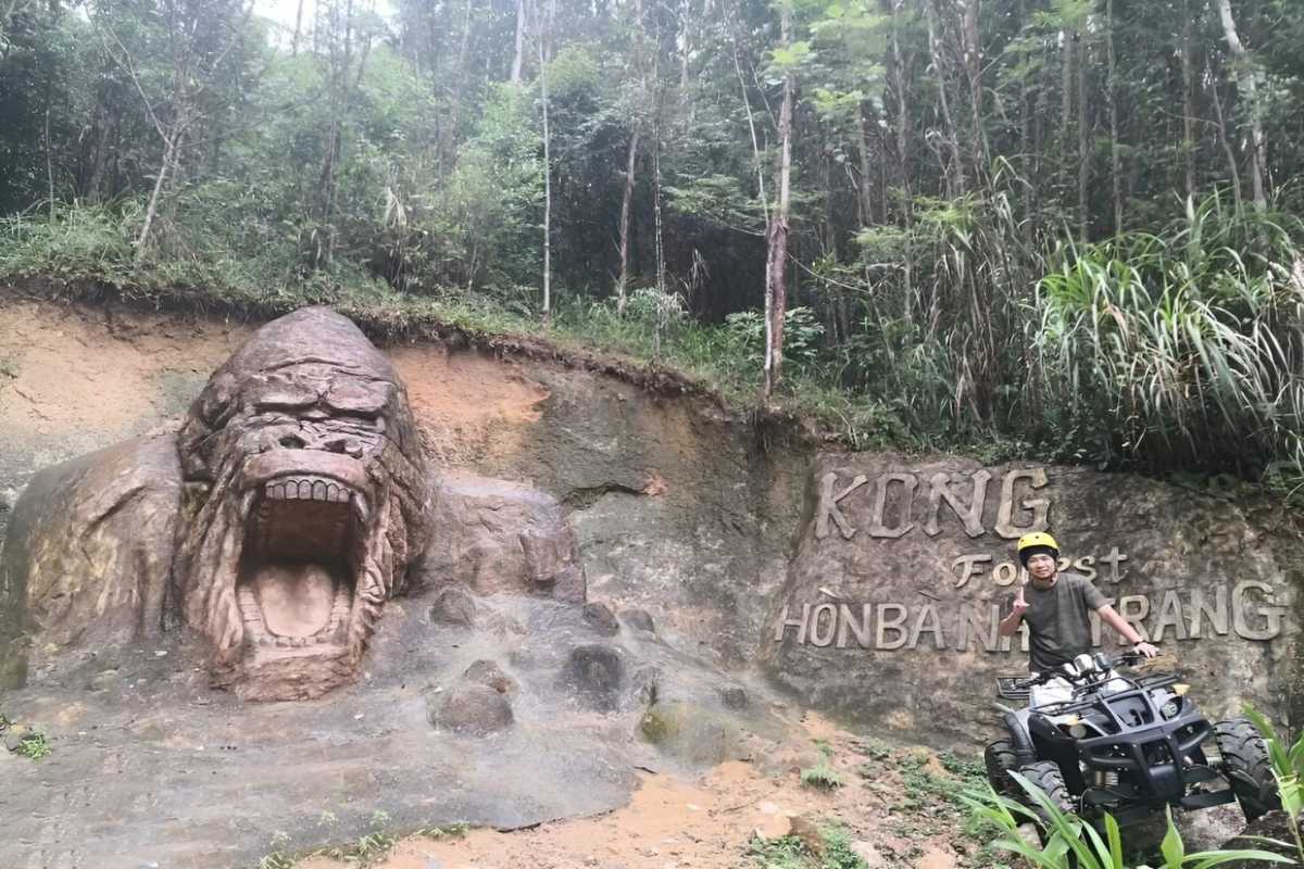 Hiker walking along a lush, green trekking path in Kong Forest at Hon Ba Nature Reserve