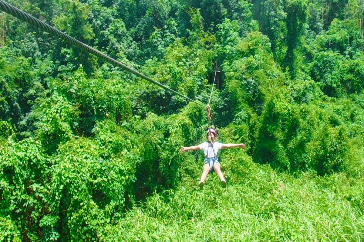Young woman enjoying a scenic zipline ride over Kong Forest canopy at Hon Ba Nature Reserve