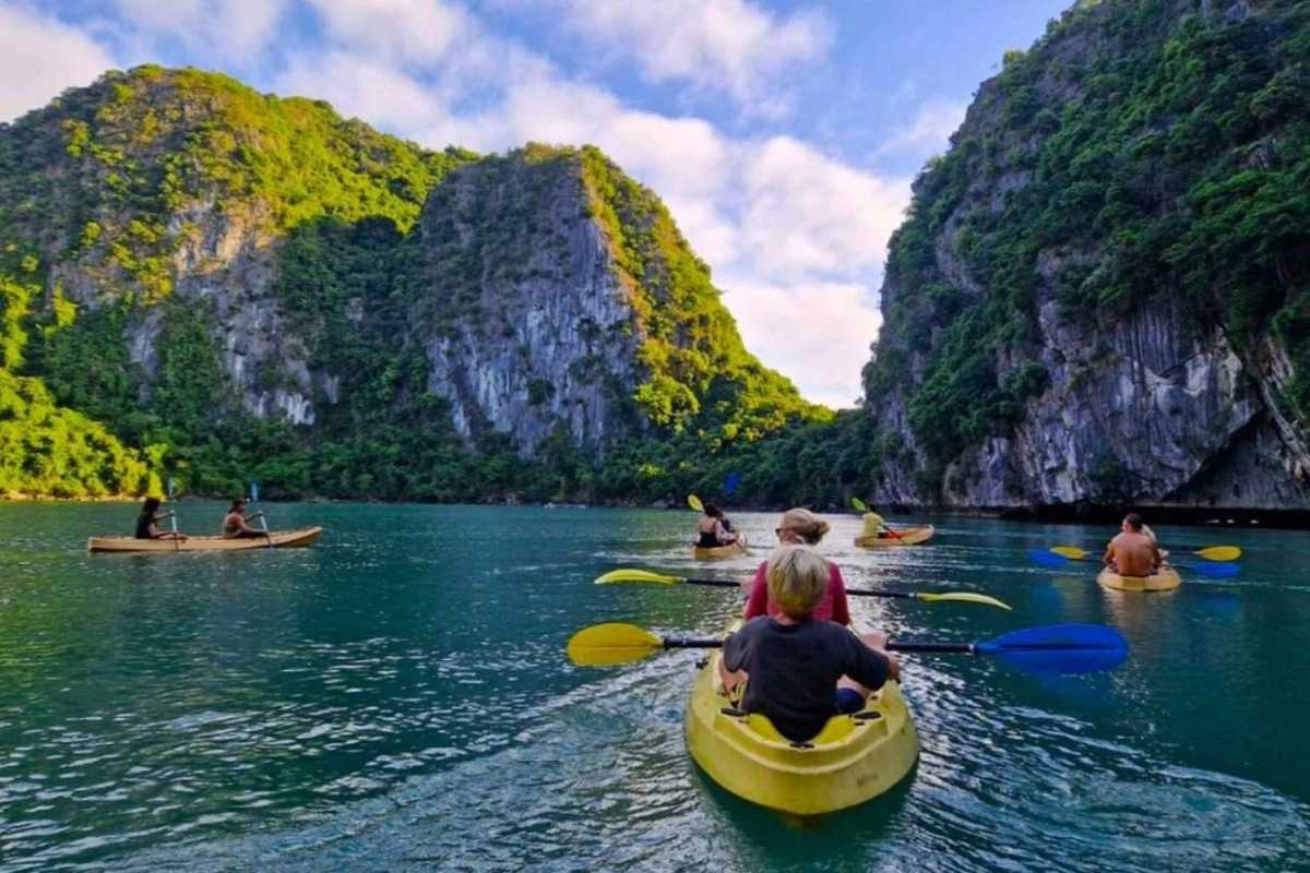 Lan Ha Bay features towering limestone islets surrounded by emerald waters and traditional boats cruising peacefully.