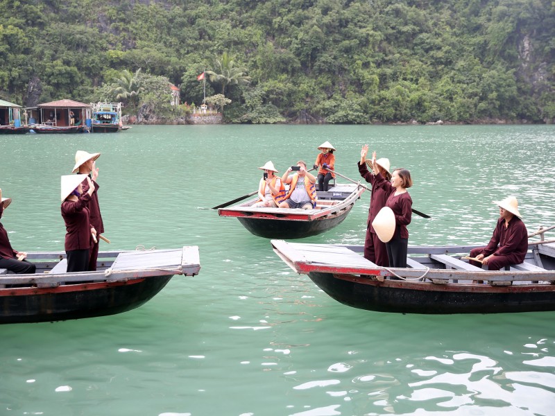 Locals and Visitors Interact at Cua Van Floating Village Local residents and tourists interact on boats at Cua Van Floating Village in Halong Bay, showcasing the village's warm hospitality.