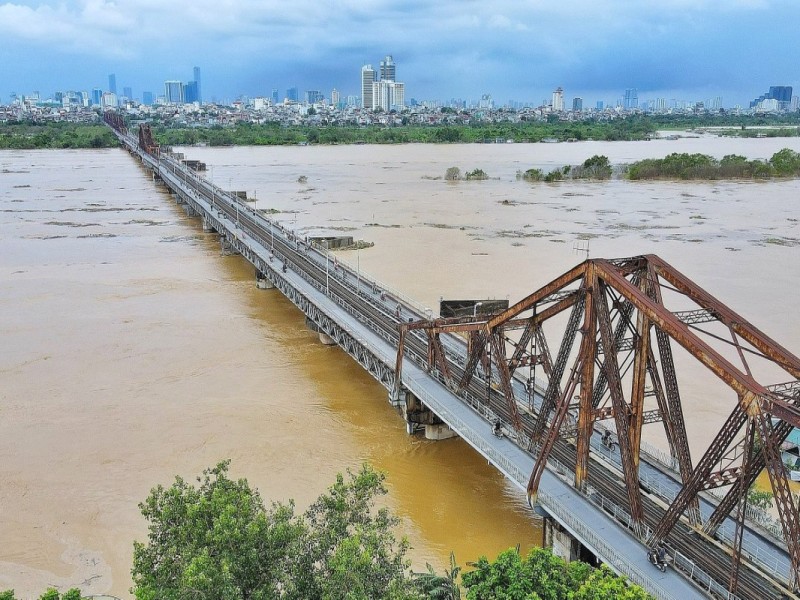 Long Bien Bridge Over the Red River The historic Long Bien Bridge stretching across the Red River, surrounded by urban Hanoi and the river's flow.