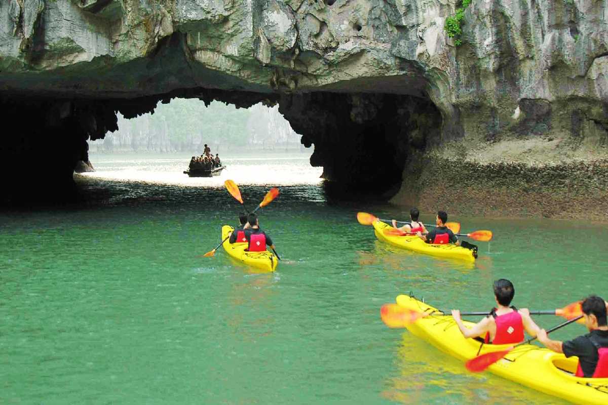 Bamboo boat tour approaching limestone cave entrance at Luon Cave, Halong Bay