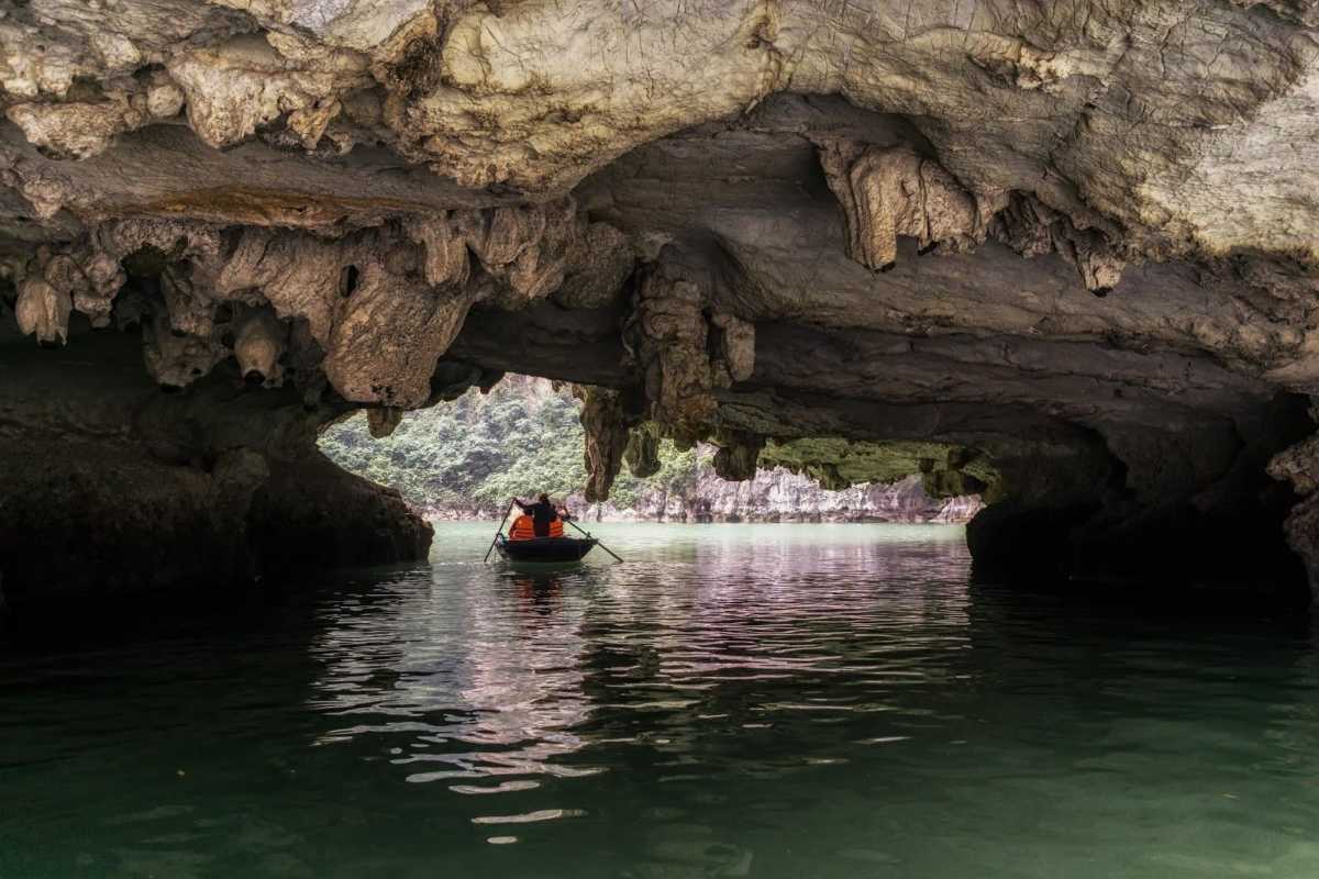 Group of tourists in a boat under the limestone formations of Luon Cave in Halong Bay