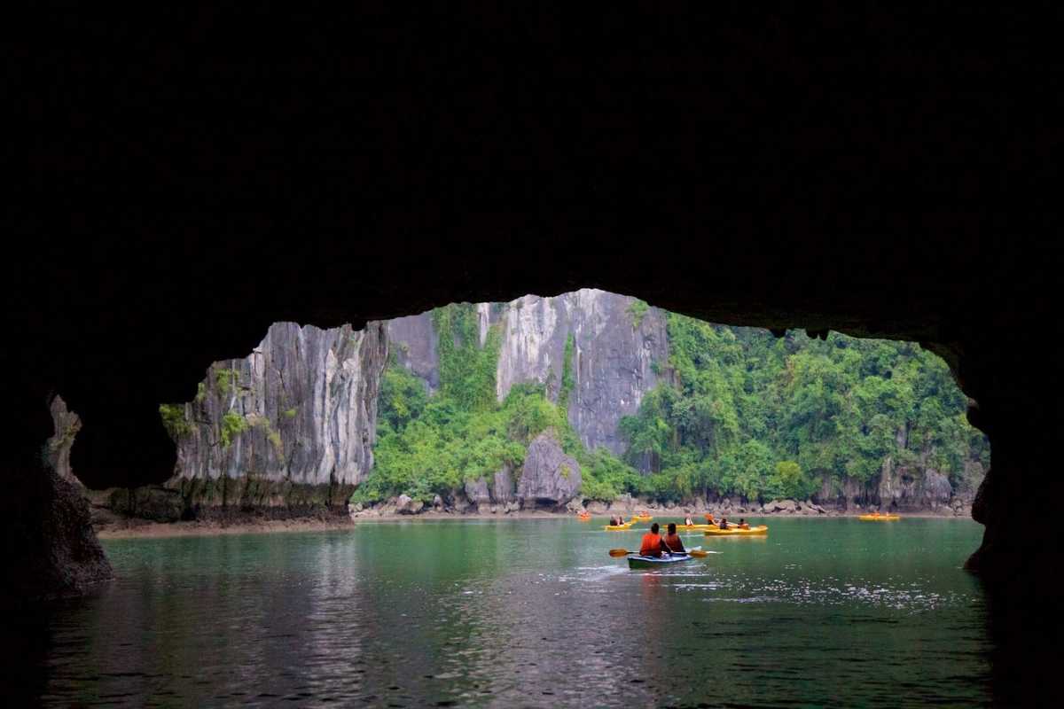 Kayakers paddling inside the limestone cave of Luon Cave, surrounded by rocky formations