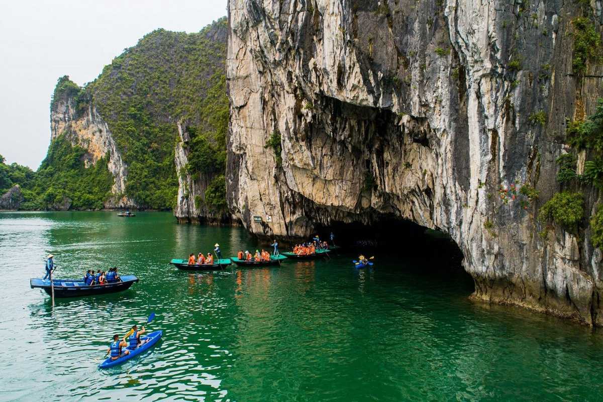 Tourists kayaking in bright kayaks inside the limestone cave of Luon Cave, Halong Bay