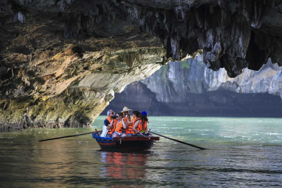 Tourists with life jackets capturing photos inside the dim limestone cave of Luon Cave