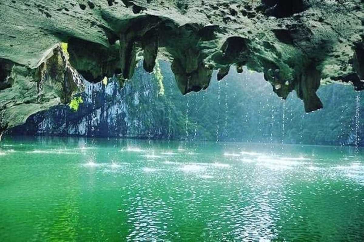 Water droplets falling from stalactites into emerald waters inside Luon Cave, Halong Bay
