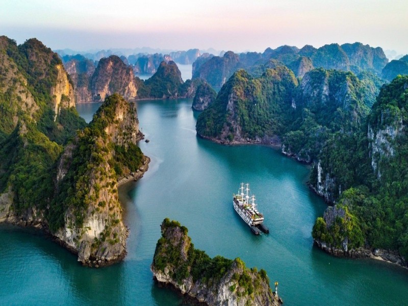 Luxury Cruise Sailing Through Cong Dam Area, Bai Tu Long Bay Luxury cruise sailing through Cong Dam Fishing Village, Bai Tu Long Bay, with limestone cliffs and calm waters.