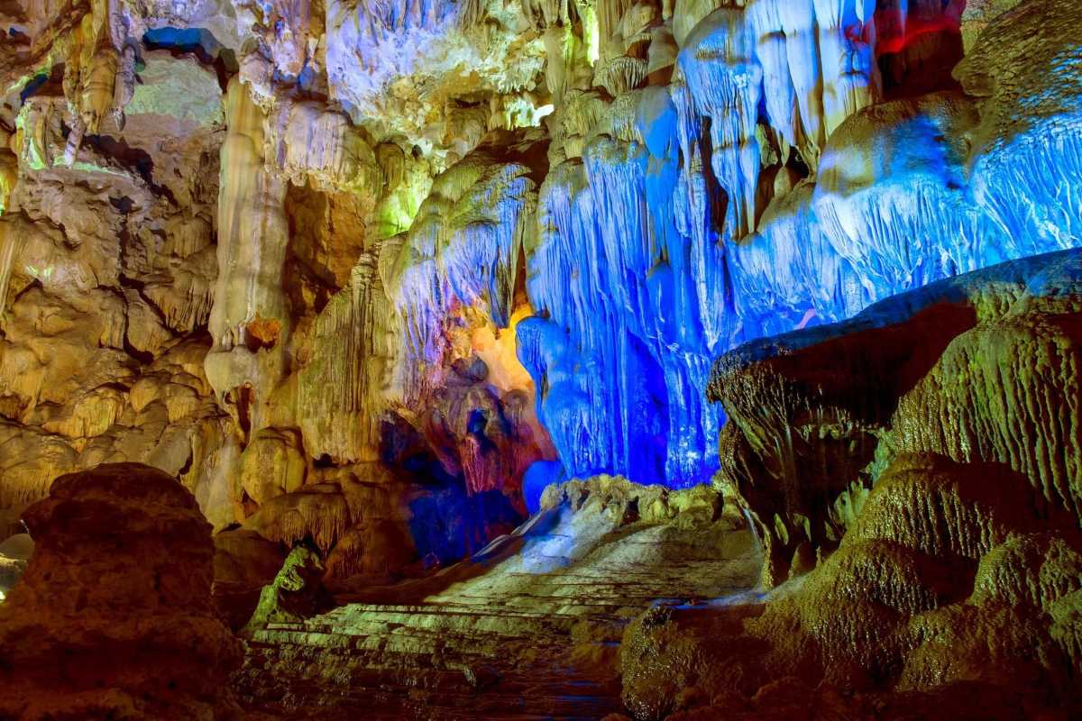 Spacious chambers inside Me Cung Cave Halong Bay with rocky walls and pathways illuminated for visitors.