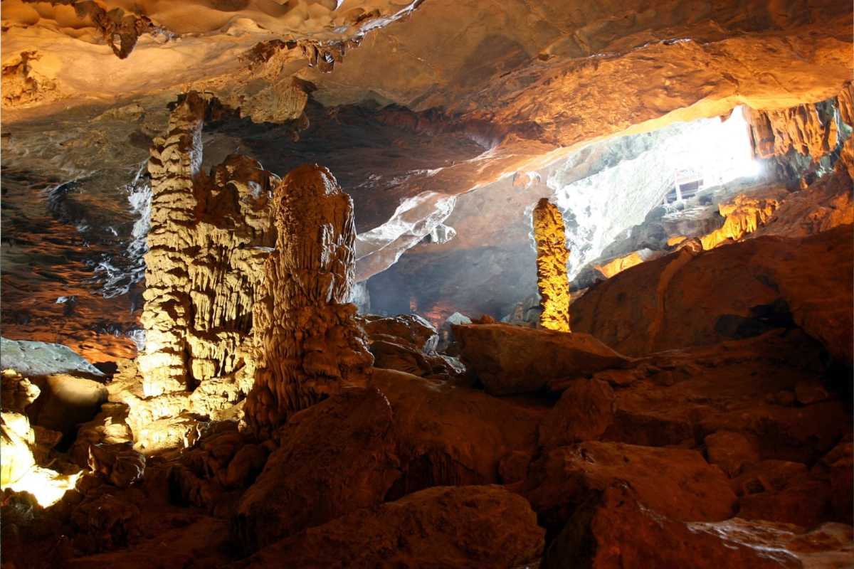 Tourists explore the illuminated interior of Me Cung Cave Halong Bay, walking along guided paths