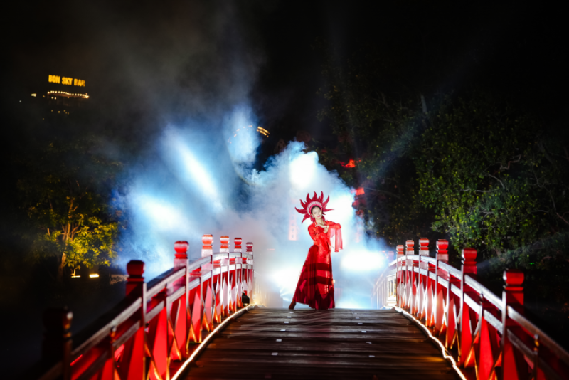 The Huc Bridge lit up at night during a traditional Vietnamese performance at Ngoc Son Temple in Hanoi