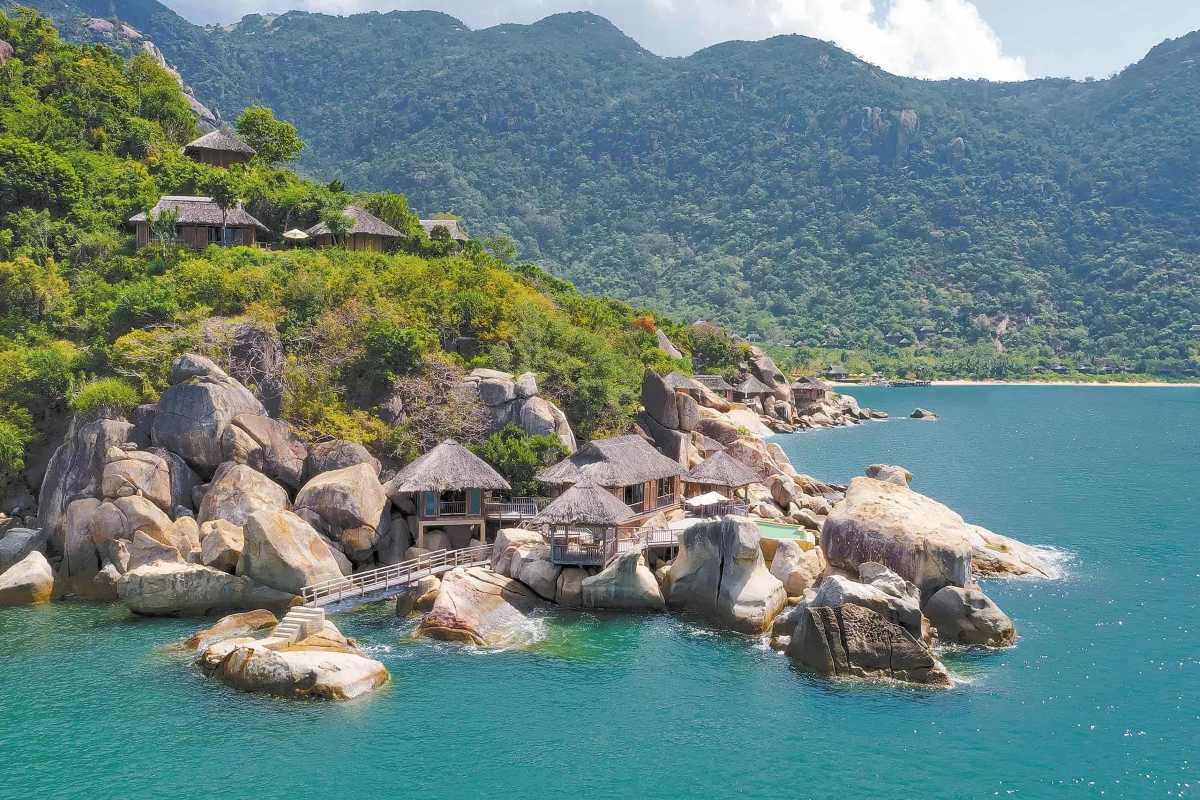 Secluded rocky beach and clear waters in Nha Phu Bay A quiet, rocky beach with clear turquoise waters surrounded by cliffs in Nha Phu Bay, ideal for relaxation and nature appreciation.