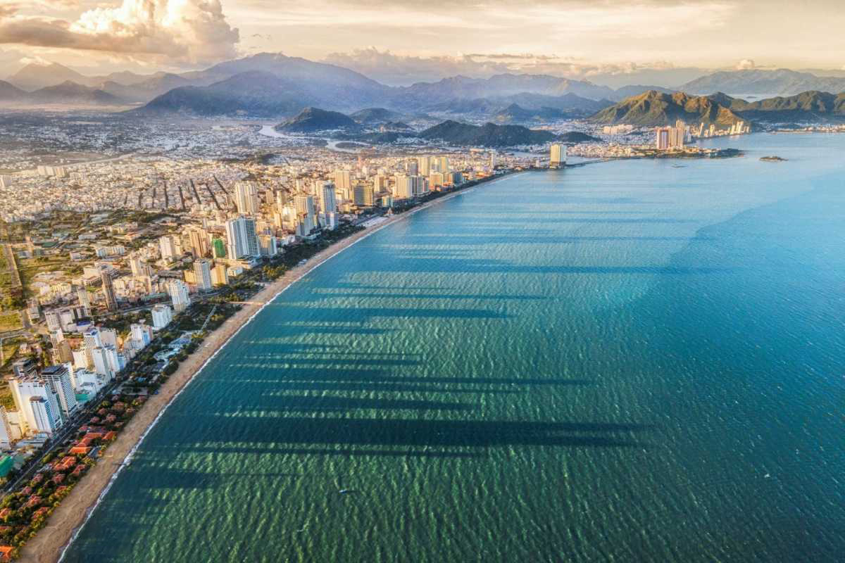 Aerial view of Nha Trang City skyline along the curved coastline during sunset, highlighting beachfront development