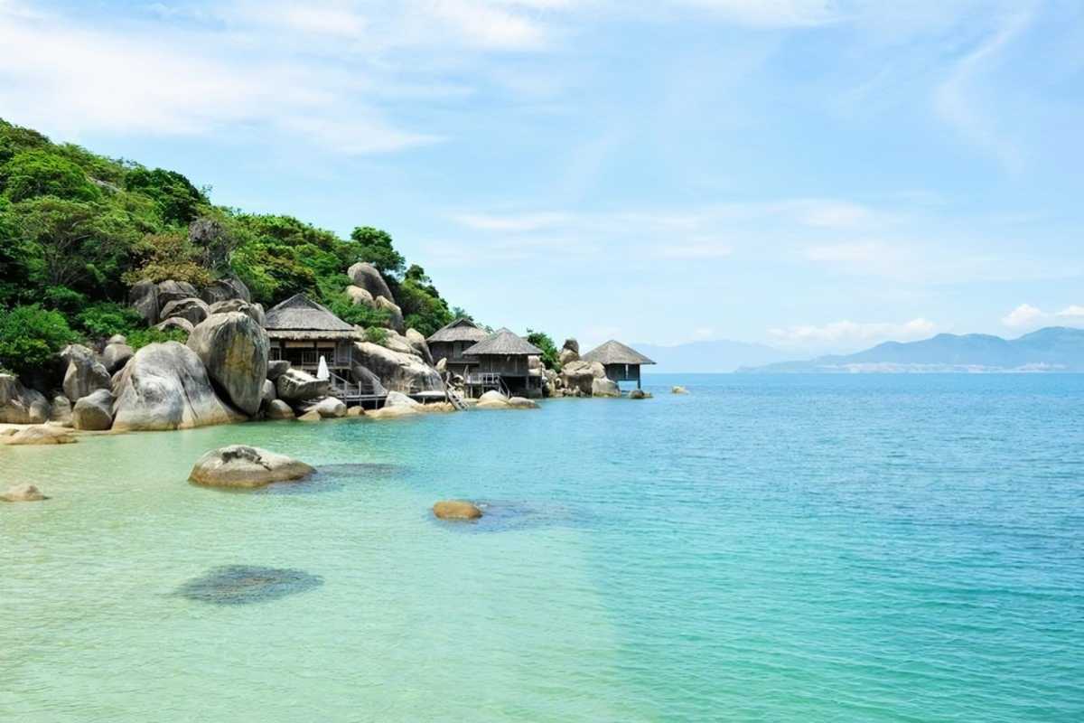 Overwater villas at Ninh Van Bay Private wooden villas over clear blue water surrounded by rocks in Ninh Van Bay.