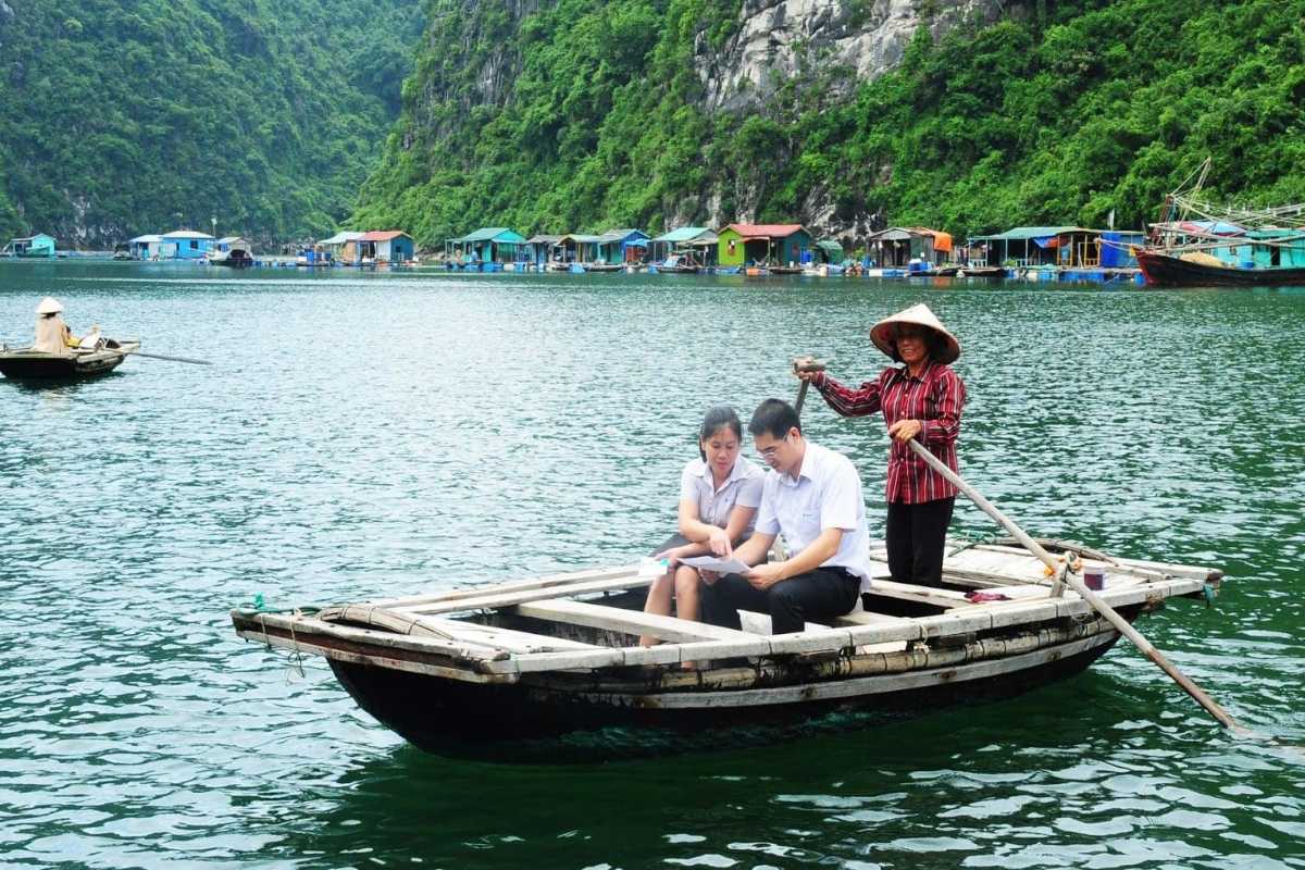 Wide panoramic shot of limestone karsts and floating fishing village in Bai Tu Long Bay